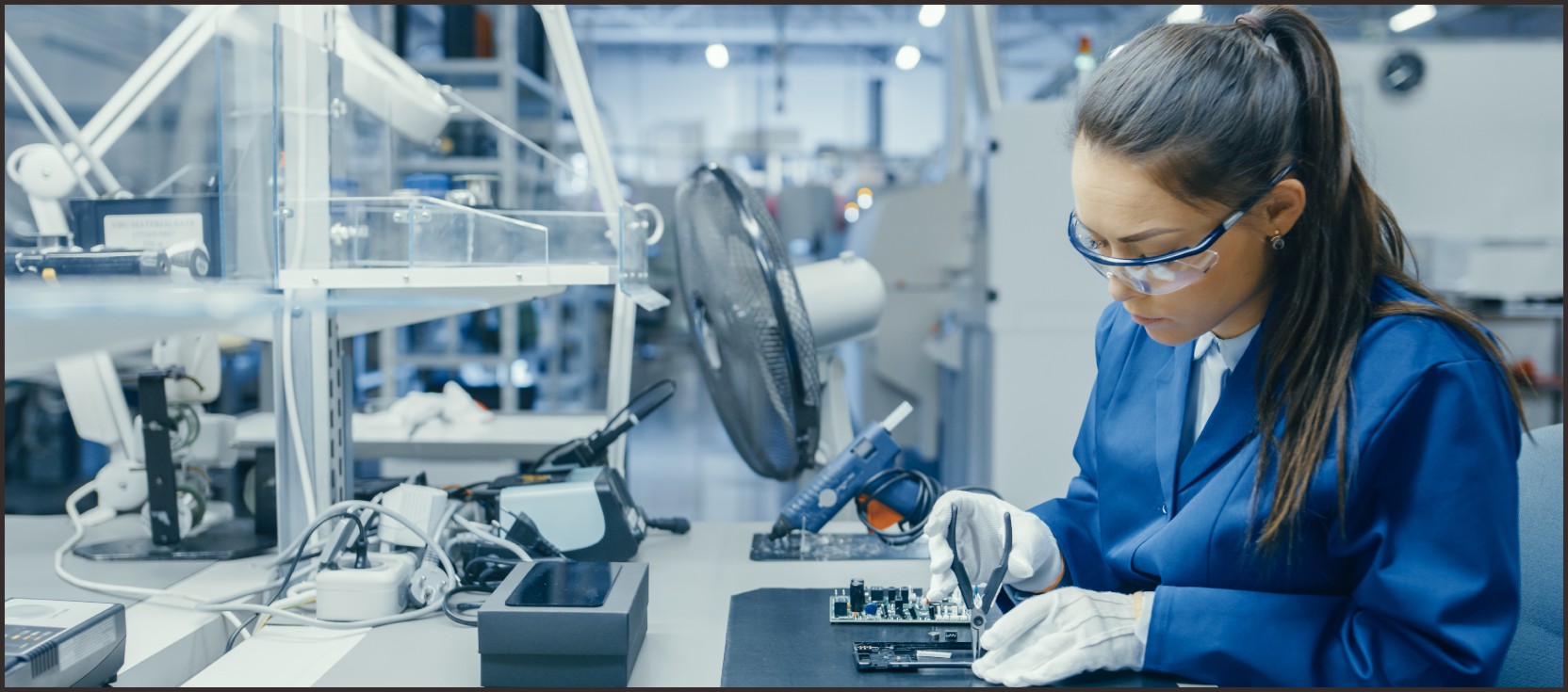 A technician in a blue lab coat and safety goggles working on a circuit board in a high-tech production facility, illustrating the customized production process from planning and management to quality inspection and continuous improvement